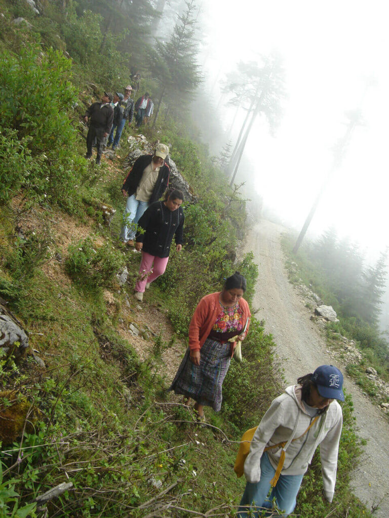 Grupo de comunidad indígena maya caminando por un sendero en la naturaleza de Kaqchikel