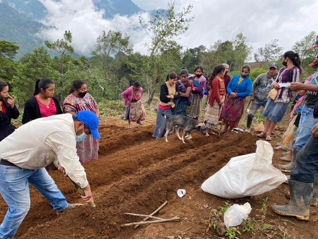 Personas indígenas de Guatemala reunidas labrando la tierra en una comunidad.